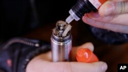FILE - A liquid nicotine solution is poured into a vaping device at a store in New York, Feb. 20, 2014. In September 2019, U.S. health officials are investigating what might be causing hundreds of serious breathing illnesses in people who vape.