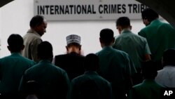 FILE - Bangladeshi police officers escort Delwar Hossain Sayeedi, center with cap, a leader of Bangladesh's largest Islamic party Jamaat-e-Islami, as he comes out after appearing before a special tribunal in Dhaka, Bangladesh, Monday, Nov. 21, 2011.