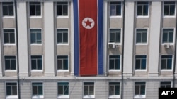 FILE - A pedestrian walks past a North Korean flag displayed on a building in Pyongyang, North Korea, April 12, 2019.