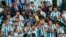 Mantan pemain Argentina Kun Aguero (tengah), memegang trofi saat ia ikut merayakan kemenangan Argentina melawan Prancis dalam Final Piala Dunia di Stadion Lusail, Qatar, 18 Desember 2022. (AP/Francisco Seco)