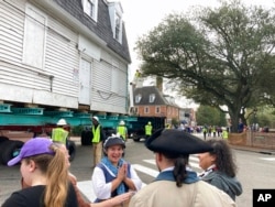 FILE - Employees of Colonial Williamsburg talk as what is believed to be the oldest schoolhouse for Black children in the United States is slowly moved down a street in Williamsburg, Va., to the living history museum, Feb. 10, 2023.