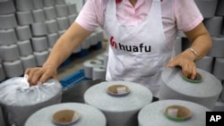 A worker packages spools of cotton yarn at a Huafu Fashion plant, as seen during a government organized trip for foreign journalists, in Aksu in western China's Xinjiang Uyghur Autonomous Region, April 20, 2021.