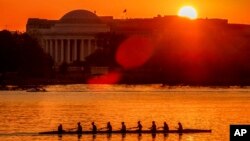 FILE - Rowers skim along the Potomac River as the sun rises over the Jefferson Memorial in Washington, May 2, 2018. 