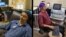 University of Washington researcher Rajesh Rao, left, plays a computer game with his mind. Across campus, researcher Andrea Stocco, right, wears a magnetic stimulation coil over the left motor cortex region of his brain. (Credit: University of Washington)