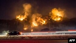 Sebuah mobil melaju melewati "Thomas Fire" yang membakar bukit sebelah selatan Casitas Springs, California, 6 Desember 2017.