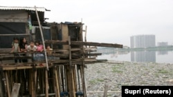 Anak-anak berdiri di dalam rumahnya di atas danau yang tercemar sampah di kawasan kumuh, Jakarta Utara. Presiden Joko Widodo meminta kemiskinan di Tanah Air dientaskan pada 2024. (Foto: REUTERS/Supri)