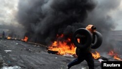 A demonstrator holds tires as he runs during a protest against Ecuador's President Lenin Moreno's austerity measures in Quito, Ecuador October 12, 2019. 