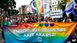 People march holding a banner that reads "Do you know who you love? Whoever you want!" march during a gay pride parade in Budapest, Hungary, July 24, 2021. 
