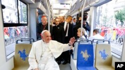 Pope Francis waves to a cheering crowd of faithful as he drives by in a public transportation tram he used to reach the venue of the World Youth Days in Krakow, July 28, 2016. 