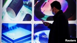 FILE - A man visits a display of semiconductor devices at Semicon China, a trade fair for semiconductor technology, in Shanghai, China, March 17, 2021. 