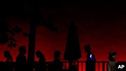 A policemen is silhouetted as he stands watch while visitors walk near Tiananmen Gate on the eve of the June 4 anniversary in Beijing, June 3, 2021. 