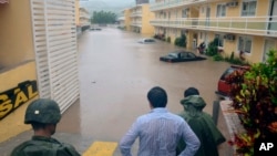 Soldados y civiles observan una calle inundada en Chilpancingo, México.