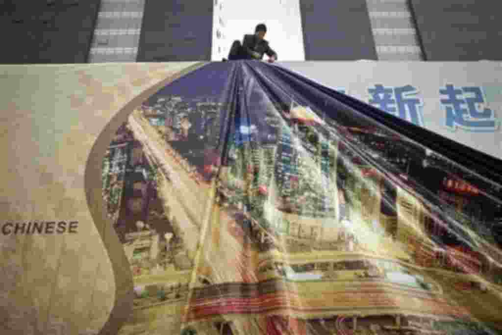 In this 13 Oct 2010 photo, a worker installs a new layer on an advertisement board showing skyscrapers in Beijing's Central Business District, China