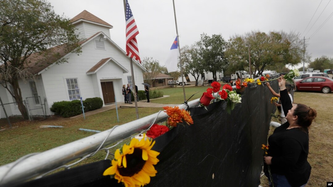 Rachel Vasquez places flowers in a fence for the victims of the shooting outside of the Sutherland Springs Baptist Church following a service held at a temporary site, Nov. 12, 2017, in Sutherland Springs, Texas.