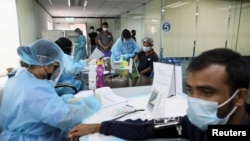 FILE - Women wait to receive the vaccine for COVID-19 in New Delhi, India, July 2, 2021.