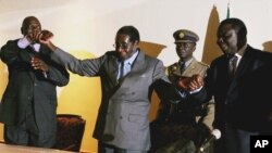 Zimbabwean President Robert Mugabe, centre, holds the hands of Morgan Tsvangirai, leader of the main opposition party, right, and Arthur Mutambara, leader of the other faction of the opposition party, at the signing of a memorandum of understanding betwee