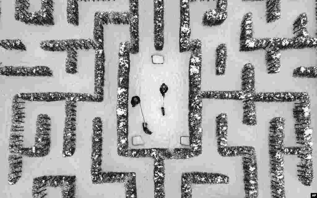 People walk with their dogs in a snow covered Garden maze in Gelsenkirchen, Germany.