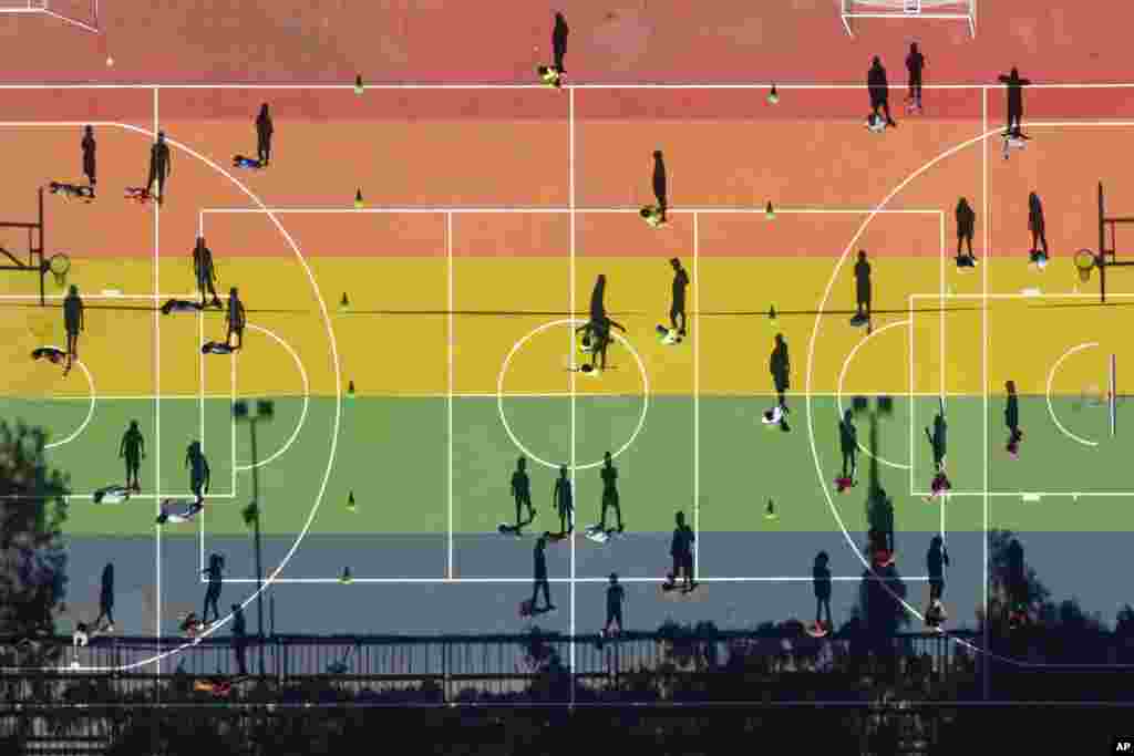 The shadows of children are cast on the court at a public park during a sports workshop organized by the municipality during school summer vacation in Santiago, Chile.