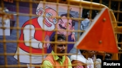 A man sits next to a poster put up during a protest by India's main opposition Congress party against Gautam Adani, after he was indicted in New York, in New Delhi, Nov. 25, 2024.