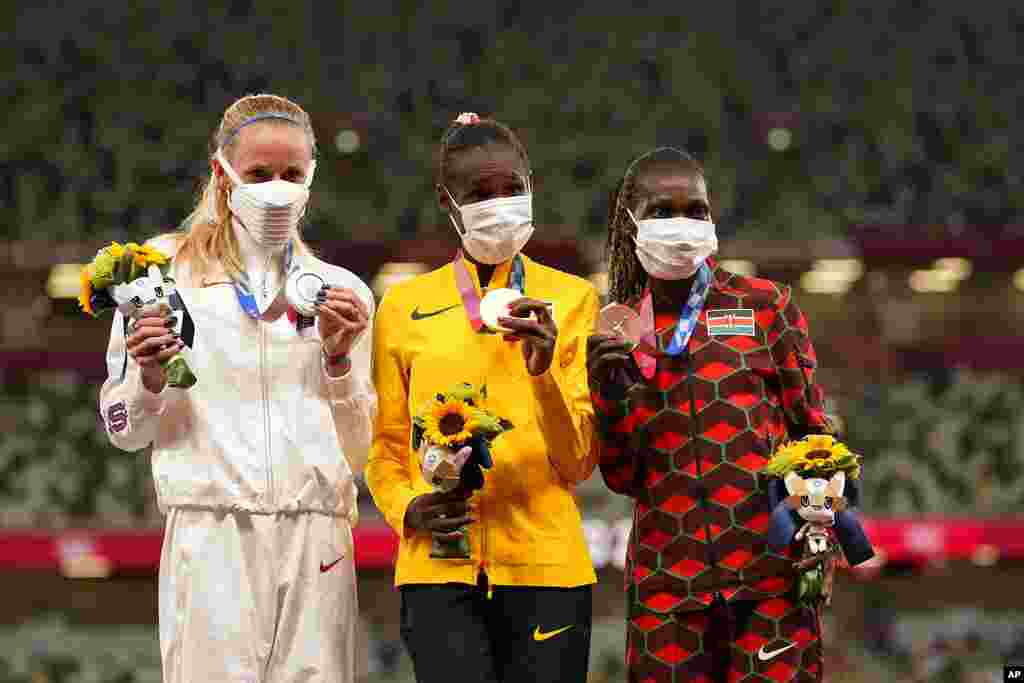 Gold medalist Peruth Chemutai, of Uganda, center, stands with silver medalist Courtney Frerichs, of the United States, left, and bronze medalist Hyvin Kiyeng, of Kenya, during the medal ceremony for the women's 3,000-meter steeplechase at the 2020 Summer Olympics, Wednesday, Aug. 4, 2021, in Tokyo. (AP Photo/Martin Meissner)