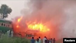 People watch fire burning a train after a gas canister passengers were using to cook breakfast exploded, near the town of Rahim Yar Khan in the south of Punjab province, Pakistan, Oct. 31, 2019, in this still image take from video. 