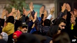 People raise their hands and shout slogans in Bucharest, Romania, during another day of protests calling for better governance and an end to corruption, Nov. 7, 2015. 