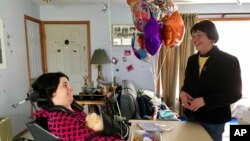 FILE - Stephanie Bushey, right, uses sign language and eye movements to communicate with her daughter, Katie, at their home in West Chazy, N.Y., March 11, 2017. Katie, who lost her vocal and motor skills at birth, relies on assistance from home health aides during the day while her mother is at work. Advocates for the disabled, elderly and chronically ill in New York are concerned the state’s move to a $15 minimum wage could deepen a shortage of home health aides. 