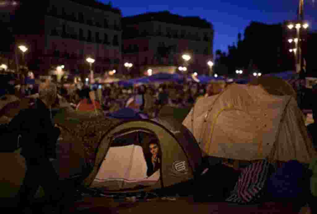 En el interior de la tienda se puede ver a un manifestante que pasa la noche en la plaza de Sol, durante una protesta en Madrid, 20 de mayo de 2011.