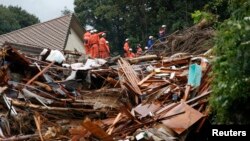 Firefighters search for survivors in the rain at a site where a landslide swept through a residential area at Asaminami ward in Hiroshima, western Japan, August 22, 2014.