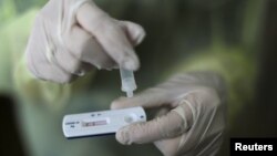 FILE - A health care worker holds a rapid COVID-19 antigen test at a coronavirus testing center in Nice, France, Oct. 15, 2020. Millions of such kits are heading to Africa for distribution.