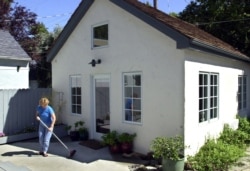 FILE — Christine Minnehan sweeps up in front of her "granny flat," a second smaller unit located in the backyard of her Sacramento, California home.