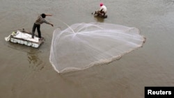 FILE - A man casts a fishing net on the Mekong riverbank in Phnom Penh, Cambodia.