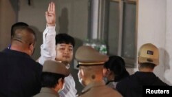 Parit Chiwarak, a pro-democracy student, one of the leaders of Thailand's recent anti-government protests, flashes a three-fingers salute as he is escorted after being arrested, at the police station in Bangkok, Thailand, Aug. 14, 2020.