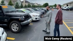 FILE: Alex Tovstanovsky, owner of used-car dealer Prestige Motor Works (left), checks on inventory with his general manager Ryan Caton in Naperville, Illinois on May 28, 2020.