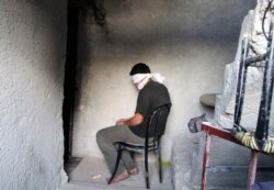 FILE - A blindfolded man waits to be interrogated in a prison in Aleppo, Syria, Oct. 6, 2014.