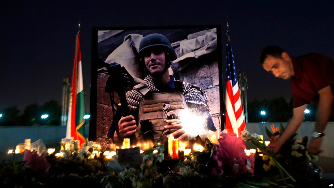 Seorang pria meletakkan bunga di sebuah tempat peringatan bagi jurnalis AS yang tewas, James Foley, di Irbil, Irak (24/8).