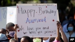  woman holds a sign during a rally protesting the shooting of Ahmaud Arbery, an unarmed black man May 8, 2020, in Brunswick Ga. 