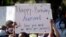 A woman holds a sign during a rally protesting the shooting of Ahmaud Arbery, an unarmed black man Friday, May 8, 2020, in Brunswick Ga. Two men have been charged with murder in the February shooting death of Arbery, whom they had pursued in a truck…