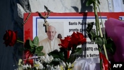 Flores, mensajes y velas para el Papa Francisco se colocan en la estatua de Juan Pablo II afuera del Hospital Universitario Gemelli, donde el Papa Francisco está hospitalizado con neumonía, en Roma, el 4 de marzo de 2025.