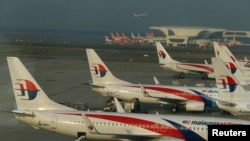 FILE - Ground crew work among Malaysia Airlines planes on the runway at Kuala Lumpur International Airport in Sepang.