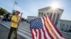 Penny Vu of Falls Church, Va., who immigrated to the United States from Vietnam 22 years ago, waves a flag as he demonstrates in front of the Supreme Court early June 25, 2018. 