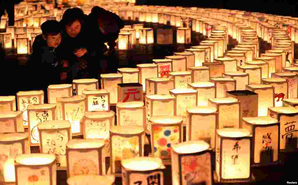 A family looks at paper lanterns during a memorial event to mourn victims of the March 11, 2011 earthquake and tsunami disaster, in Natori, Miyagi prefecture, Japan, in this photo taken by Kyodo March 11, 2017.