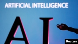 Las iniciales en glés de Inteligencia Artificial, pueden observarse en una pantalla gigante junto a una miniatura de mano de robot en esta ilustración tomada el 23 de junio de 2023.