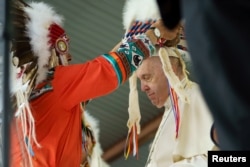 Pope Francis is given a headdress by Chief Wilton "Willie" Littlechild, during a visit where he apologized to Canada's native people on their land for the church's role in schools where Indigenous children were abused in Maskwacis, Alberta, July 25, 2022. (Adam Scotti/Prime Minister's Office/Reuters)