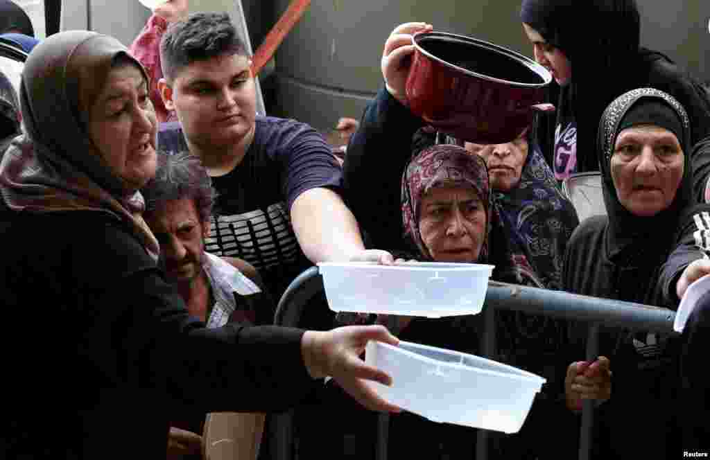 Displaced people queue for food cooked by a charity kitchen, amid ongoing hostilities between Hezbollah and Israeli forces, in downtown Beirut, Lebanon.