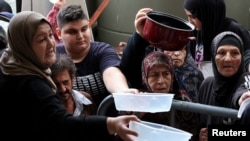 Displaced people queue for food cooked by a charity kitchen, amid ongoing hostilities between Hezbollah and Israeli forces, in downtown Beirut, Lebanon.