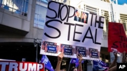 President Donald Trump supporters gather with signs claiming a stolen election outside the Philadelphia Convention Center as they await general election tabulation results, in Philadelphia, Nov. 6, 2020.