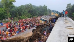Warga berkumpul dekat gerbong kereta yang rusak parah akibat bertabrakan di distrik Brahmanbaria, 82 kilometer timur ibukota, Dhaka, Bangladesh, Selasa, 12 November, 2019.