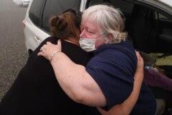 Margi Wyatt, right, is comforted by a friend after returning home to find her mobile home destroyed by wildfire in Estacada, Ore., Sept. 12, 2020.