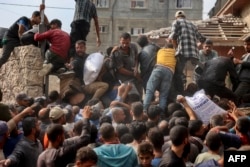 People scramble to receive sacks of flour at a United Nations Relief and Works Agency (UNRWA) aid distribution center in Deir el-Balah in the central Gaza Strip, Nov. 3, 2024, amid the war between Israel and the Palestinian militant group Hamas.